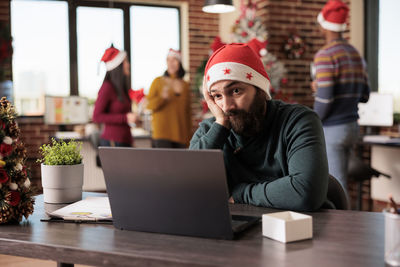 Young man using laptop while sitting on table