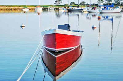 Still life red sailboat moored and  reflected in tranquil sea