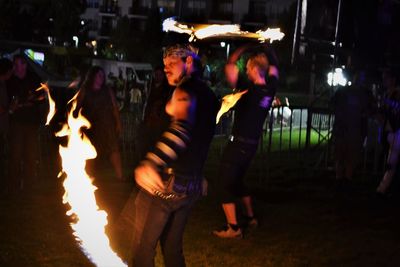 People standing against illuminated fire at night