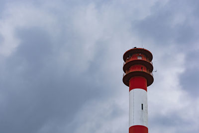 Low angle view of lighthouse by building against sky