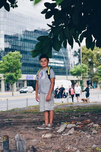 Portrait of happy boy standing against tree