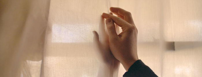 Cropped hands on curtain at home
