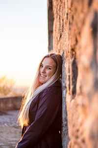 Portrait of smiling woman standing against wall