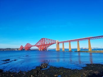 Railbridge over sea against clear blue sky