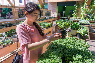 Portrait of young woman standing against plants