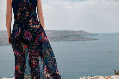 Midsection of woman standing on cliff against sea