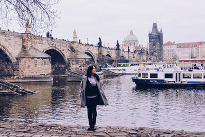 Full length of woman standing by river in city