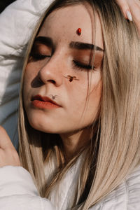 Close-up of young woman with ladybug on face