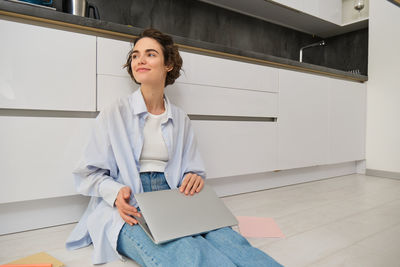 Portrait of young woman standing against building