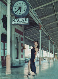 Full length portrait of woman standing against sign