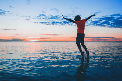 Rear view of man standing in sea against sky
