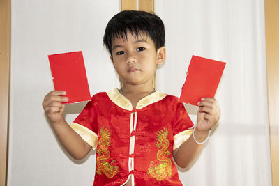 Boy holding red while standing at home