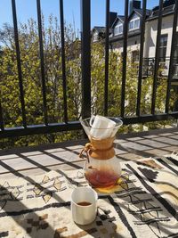 Tea cup on table by railing against trees