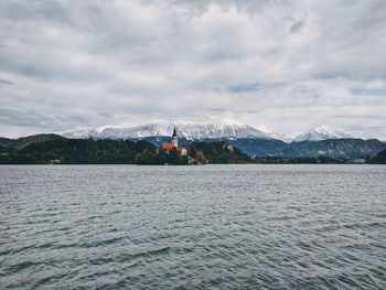 Scenic view of lake bled by snowcapped mountains against sky in autumn.