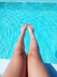 Low section of woman relaxing at poolside