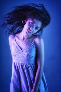 Portrait of a smiling young woman against blue background