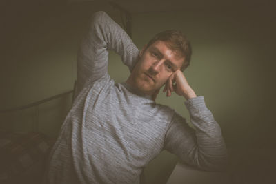 Portrait of man sitting against wall at home