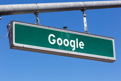 Low angle view of road sign against blue sky