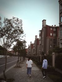 Rear view of people walking on road in city