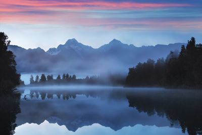 Scenic view of lake by trees against sky