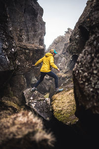 Woman in yellow jacket exploring thermal fissures in iceland