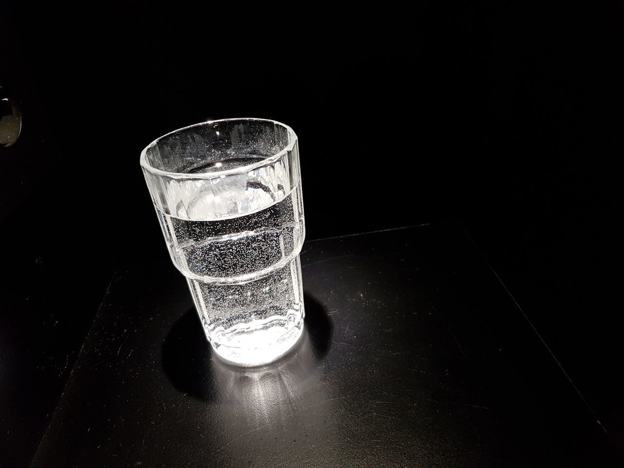 CLOSE-UP OF WINE GLASS ON TABLE AGAINST BLACK BACKGROUND