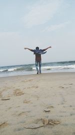 Full length of boy standing on beach against sky