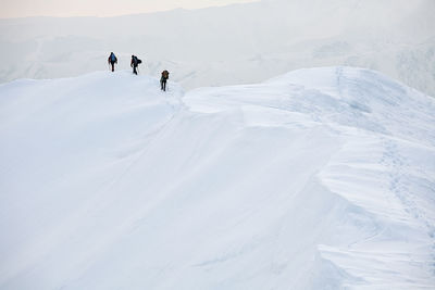 Rear view of people climbing on snow covered mountains