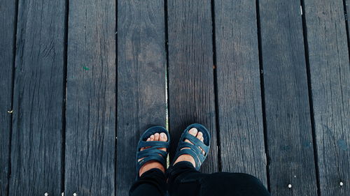 Low section of man standing on wooden floor