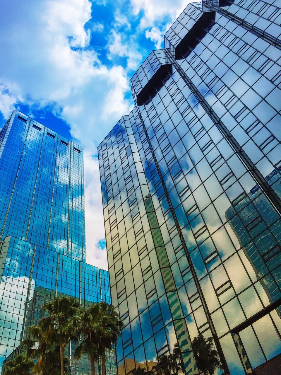 building exterior, architecture, low angle view, built structure, modern, office building, skyscraper, tall - high, glass - material, city, reflection, tower, sky, building, cloud - sky, blue, day, cloud, tall, window