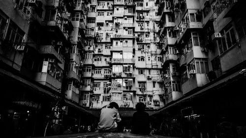 Rear view of people sitting against buildings