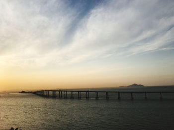 Bridge over sea against sky during sunset