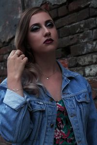 Close-up of beautiful woman with make-up standing by brick wall