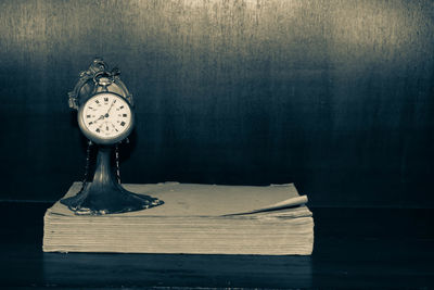 Close-up of clock on table against wall