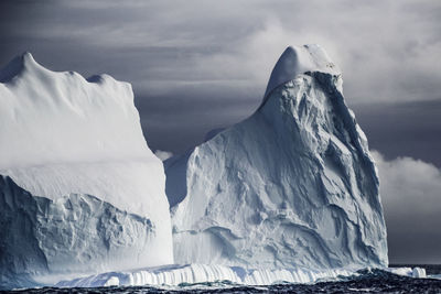 Scenic view of icebergs against cloudy sky