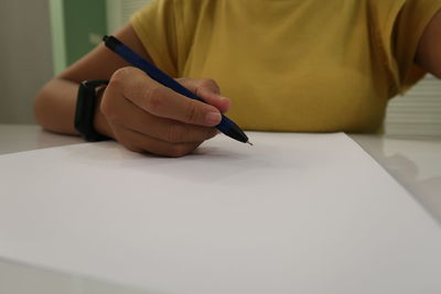 Midsection of man holding paper while sitting on table