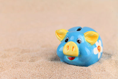 Close-up of piggy bank on sand