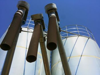 Low angle view of industry against clear blue sky