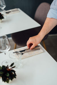 Hand of male waiter setting a table in a restaurant