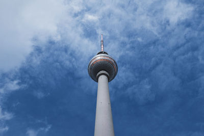 Low angle view of communications tower against cloudy sky