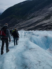 Rear view of people walking on snow covered mountain