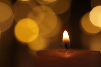 Close-up of lit candle in dark room with bokeh 