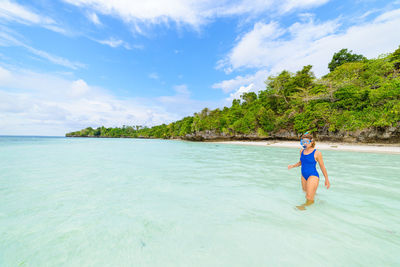 Woman on sea shore against sky