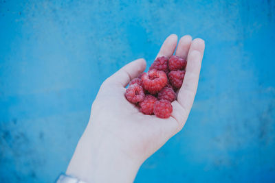 Midsection of person holding ice cream against blue sky