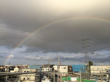 Rainbow over buildings in city against sky