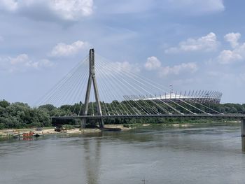 Suspension bridge over river against sky