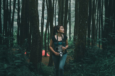 Young woman walking against tree at forest