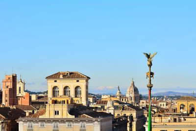 Buildings in city against clear blue sky