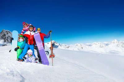 Low angle view of woman skiing on snow covered landscape against clear blue sky