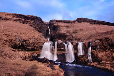 Scenic view of waterfall against sky